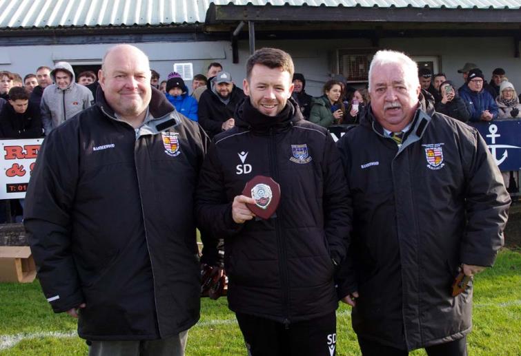 Division 1 league winning Hakin United manager Scott Davies receives his medal from League Council members Ian Baker and Mackie Harts